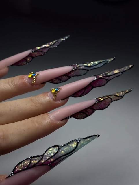 Unghie stiletto con nail art effetto ali nere e dettagli oro
